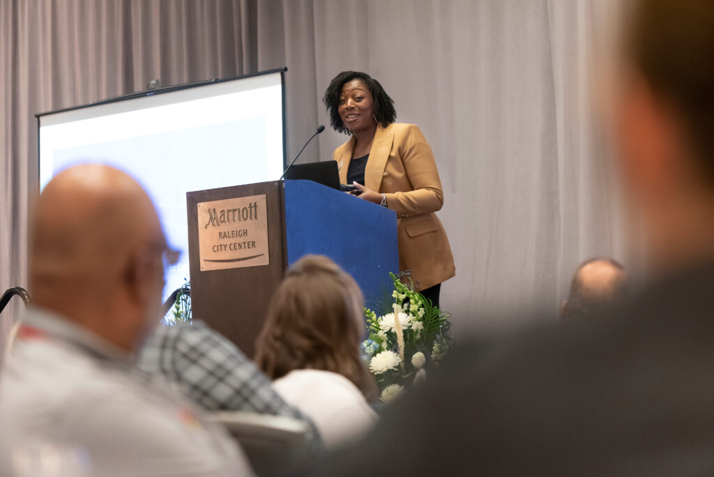 Deputy Director Monica Clark speaks from a podium to an audience at a Belk Center convening.